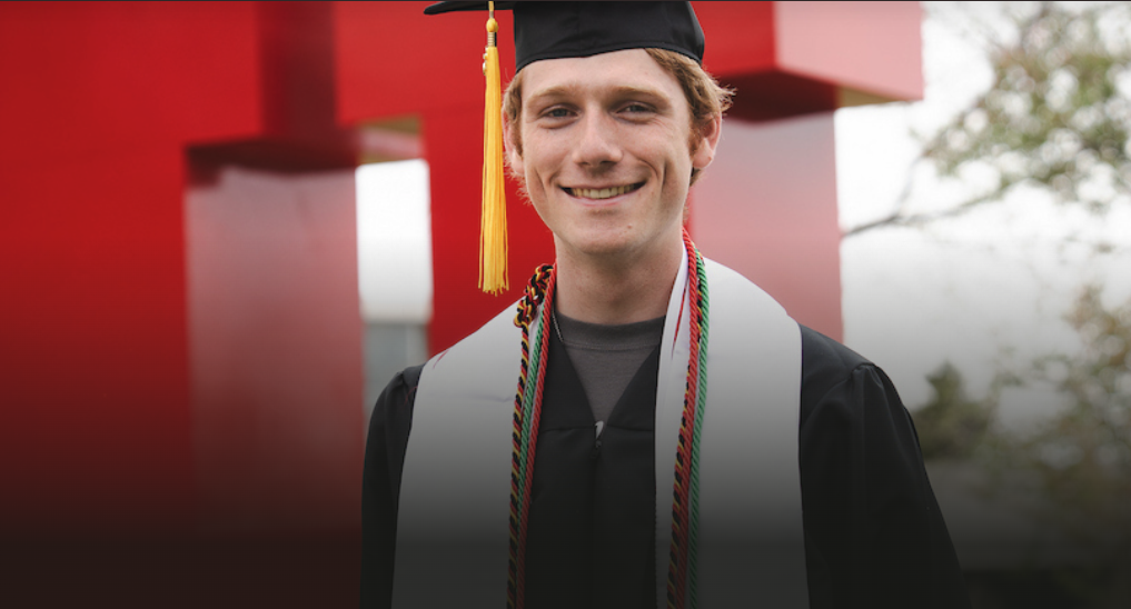 Marcus Tanner in graduation regalia in front of the block U.
